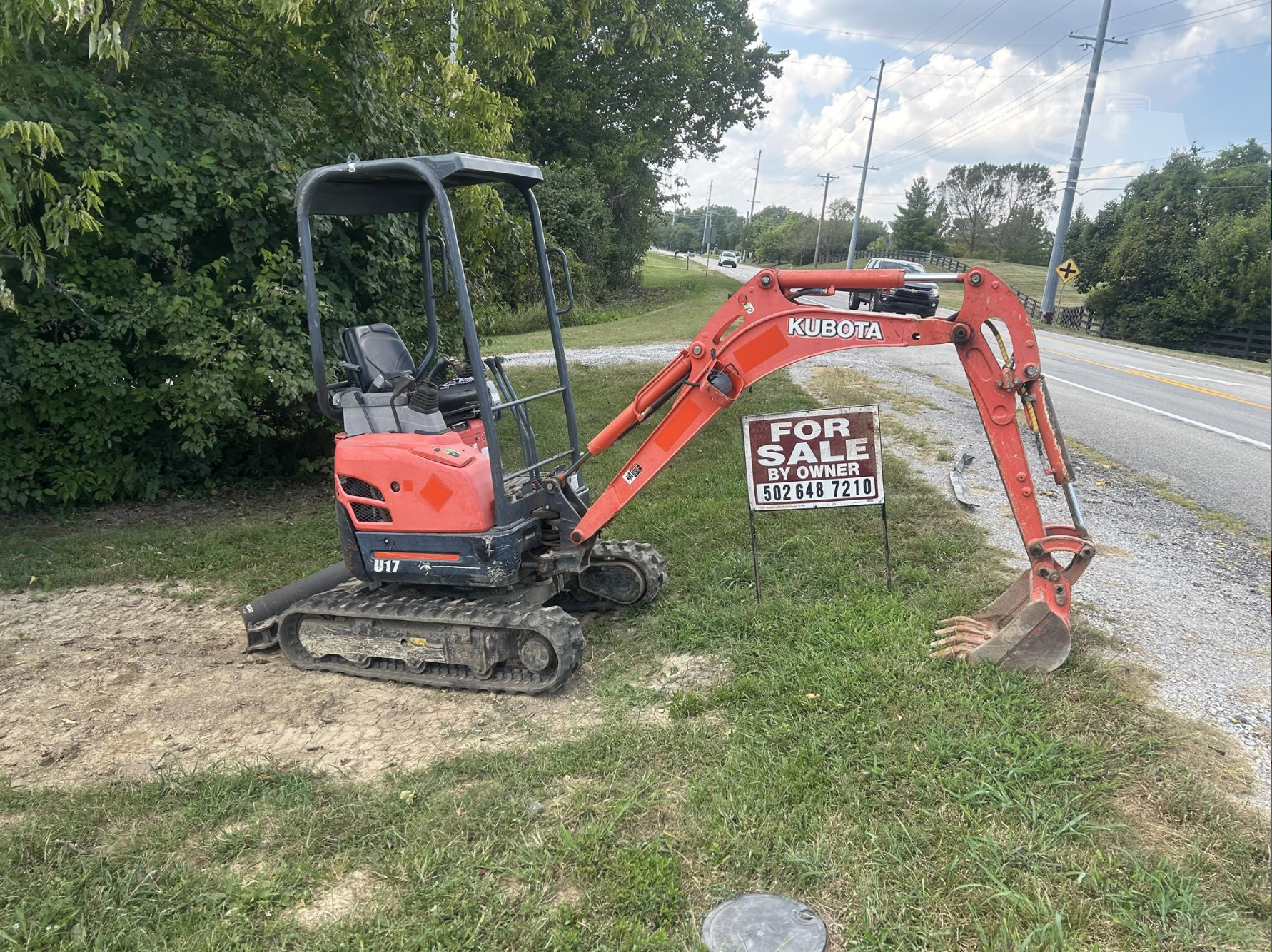 Red Kubota mini excavator beside the road